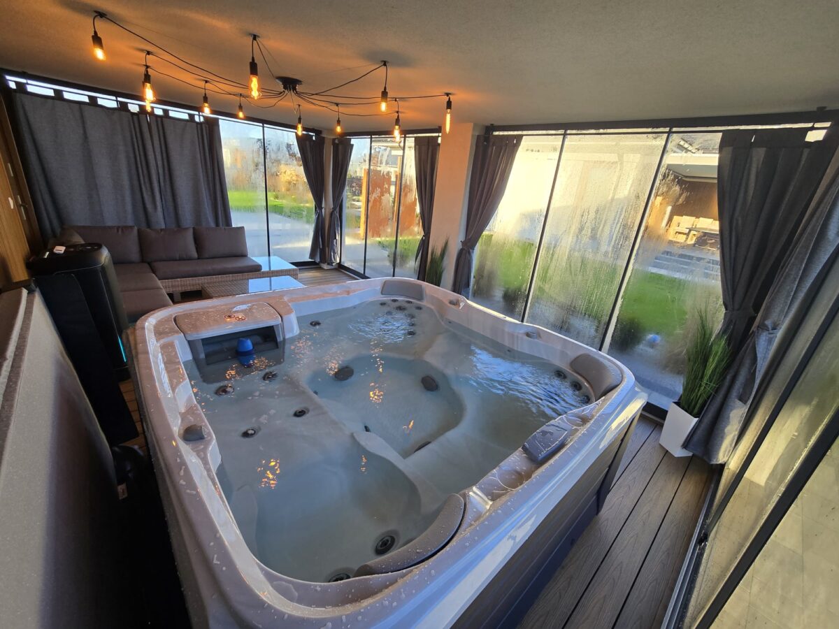 Nowoczesne jacuzzi w przeszklonej strefie relaksu stanowiącej przedłużenie domu