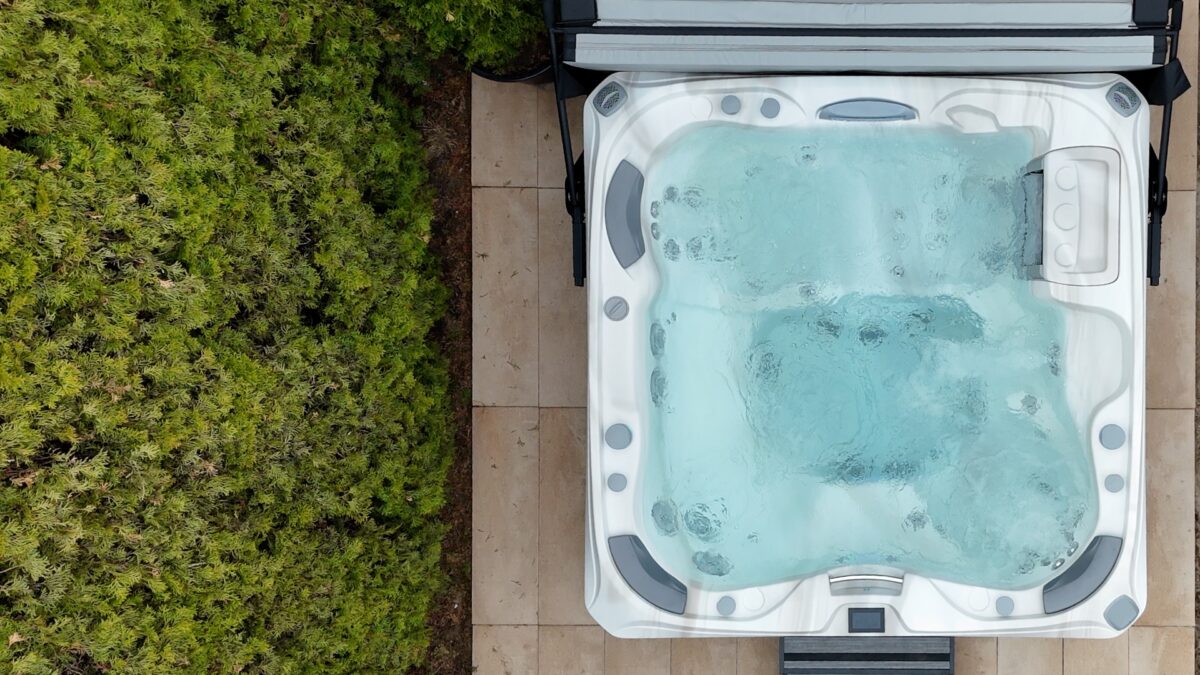 Nowoczesne jacuzzi w ogrodzie ustawione blisko domu w otoczeniu roślin zapewniających prywatność